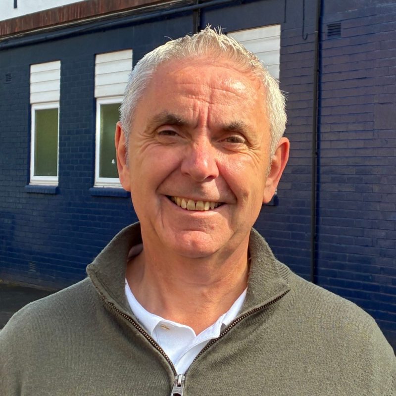 A photo of Paul Dawson from Stockport County Supporters Cooperative stood outside the Stockport County sign at Edgeley Park, Stockport.