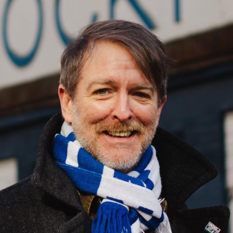 A photo of Paul Thompson from Stockport County Supporters Cooperative stood outside the Stockport County sign at Edgeley Park, Stockport.